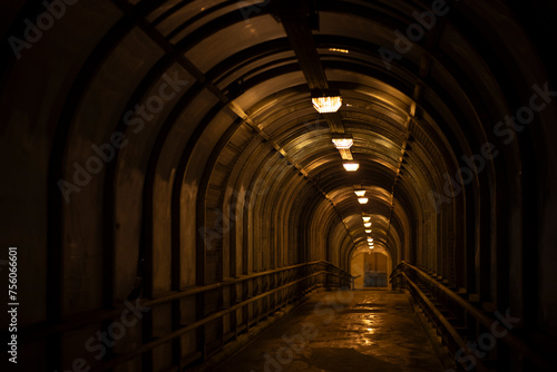 Tunnel in the dark. Pedestrian crossing through a tunnel above the road. Long corridor.