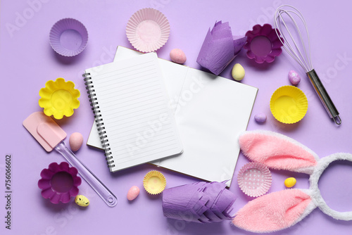 Blank notepads for recipes with Easter eggs, bunny ears and baking tools on lilac background