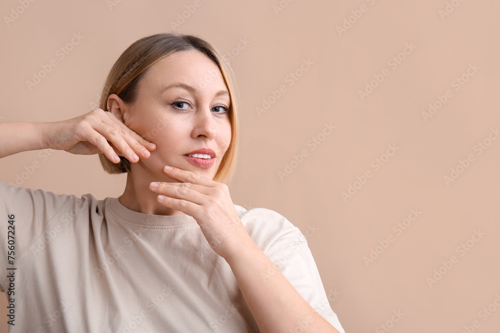 Woman doing face building exercise on beige background Woman doing face building exercise on beige background