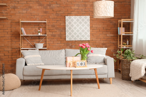 Interior of modern living room with flowers, gift box and calendar on coffee table in living room photo