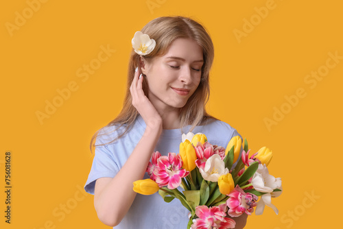 Pretty young woman with bouquet of beautiful tulips on yellow background