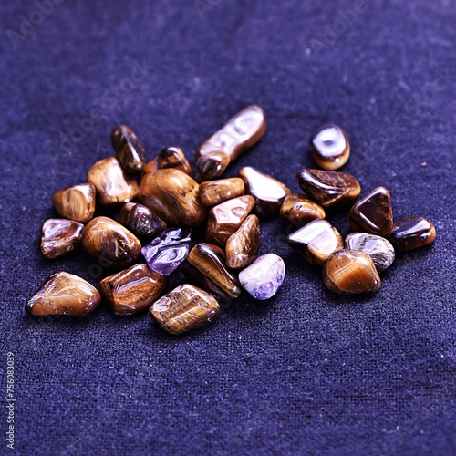 Several tigers eye gem stones or healing crystals laying on cotton fabric.  (ID: 756083039)