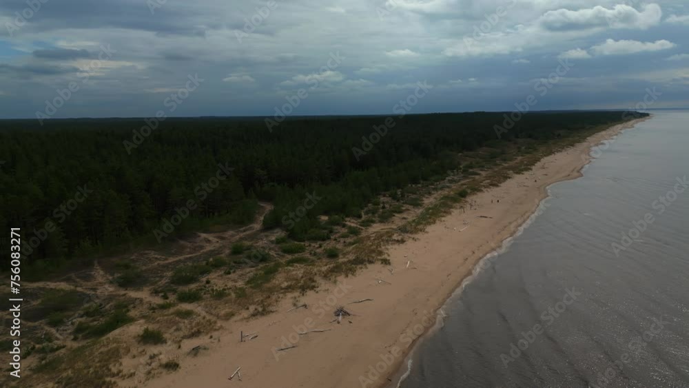Coastal beauty: Aerial shot captures a sandy beach beside water under a cloudy sky Coastal beauty: Aerial shot captures a sandy beach beside water under a cloudy sky