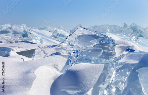 Winter natural background with fragments of blue snowy ice and heaps of pieces of ice floes on frozen Baikal Lake on sunny frosty day. Abstract cold background. Harsh lifeless north environment