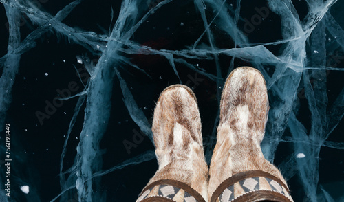 Top view of woman traditional Siberian fur footwear on beautiful blue ice with cracks of Baikal Lake. Warm unts or fur boots are made from reindeer skins using old technologies of local residents photo