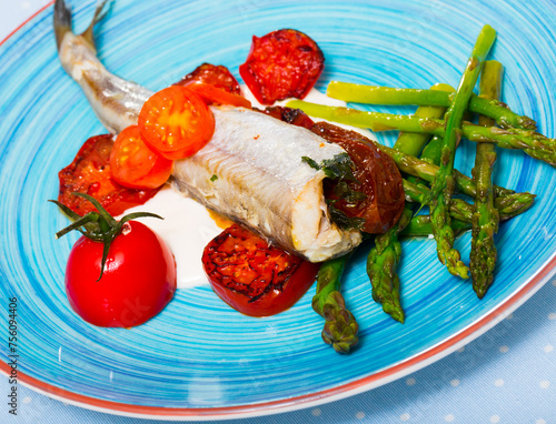 Tasty baked fish poutassou with dried tomatoes, asparagus and creamy-garlic sauce photo