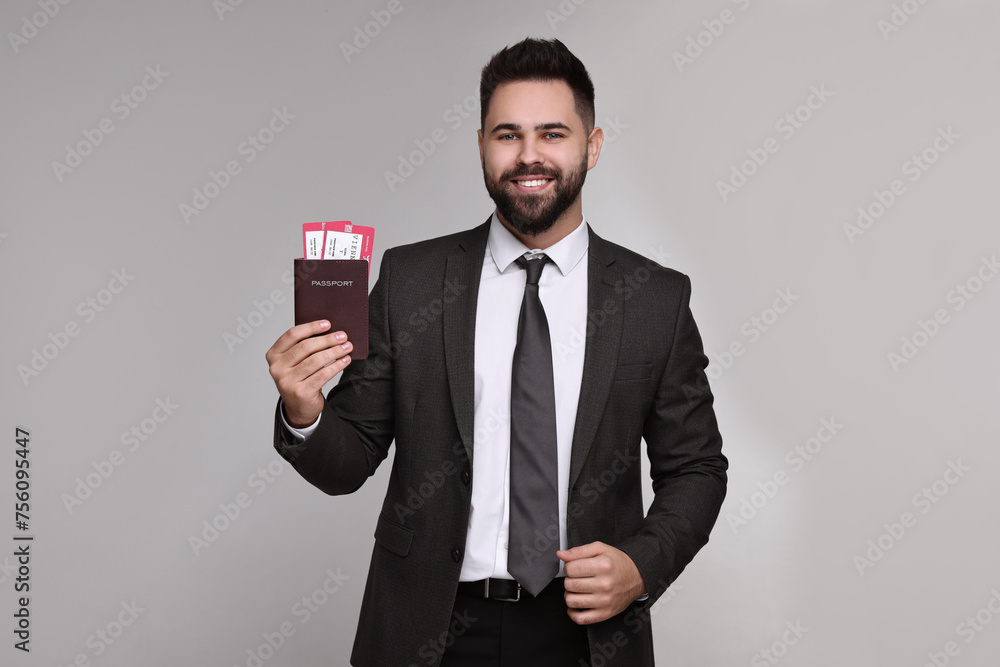 Happy businessman with passport and tickets on grey background Happy businessman with passport and tickets on grey background