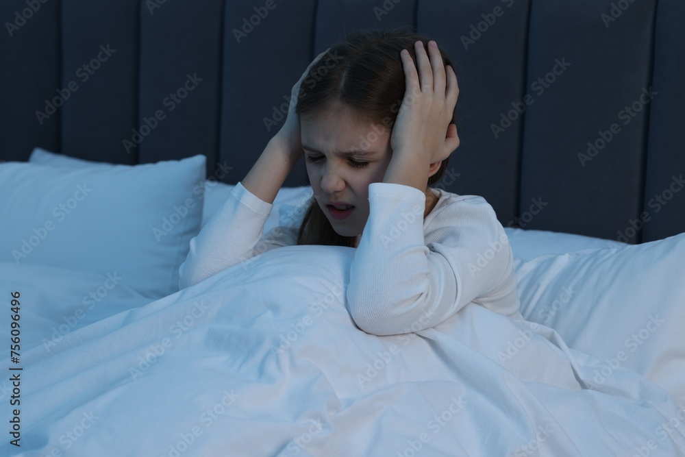 Little girl suffering from headache in bed at night Little girl suffering from headache in bed at night