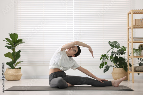 Girl practicing revolved head to knee asana on mat in yoga studio. Parivrtta janu sirsasana pose photo