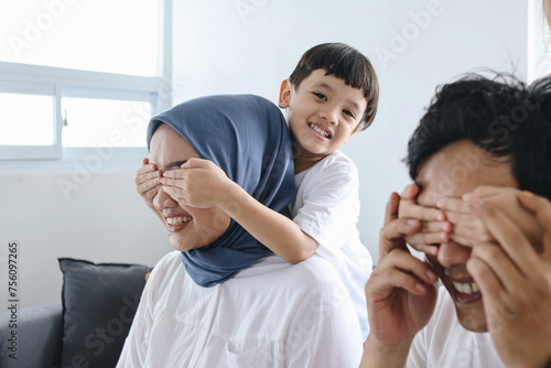 Kids closing eyes of parents using hands giving surprise. Family bonding at home, playing hide and seek. 