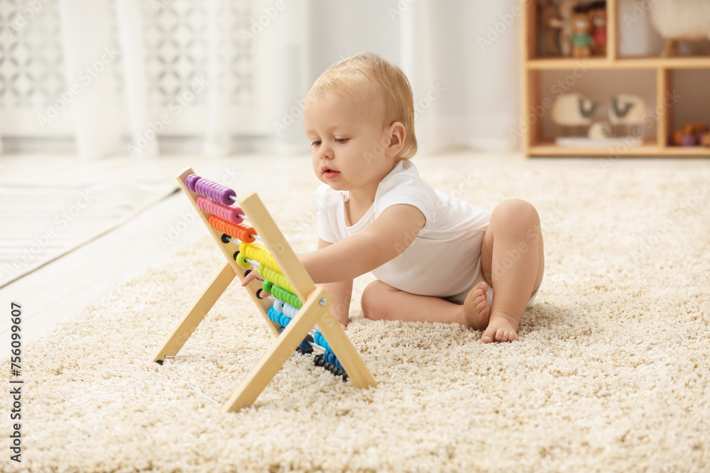 Children toys. Cute little boy playing with wooden abacus on rug at home Children toys. Cute little boy playing with wooden abacus on rug at home
