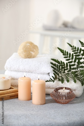 Spa composition. Burning candles  soap  towels and loofah on soft grey surface