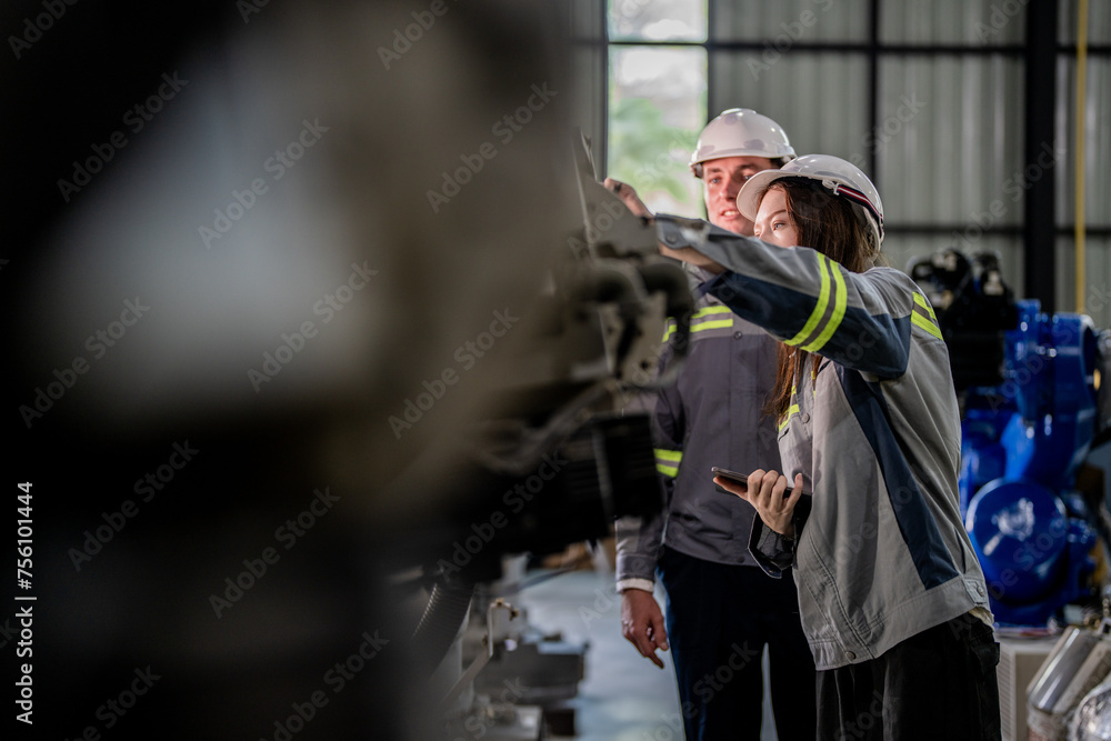 Factory engineer woman inspecting on machine with smart tablet. Worker works at machine robot arm. The welding machine with a remote system in an industrial factory. Artificial intelligence concept. Factory engineer woman inspecting on machine with smart tablet. Worker works at machine robot arm. The welding machine with a remote system in an industrial factory. Artificial intelligence concept.