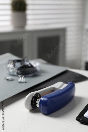 Stapler on white table indoors  closeup view