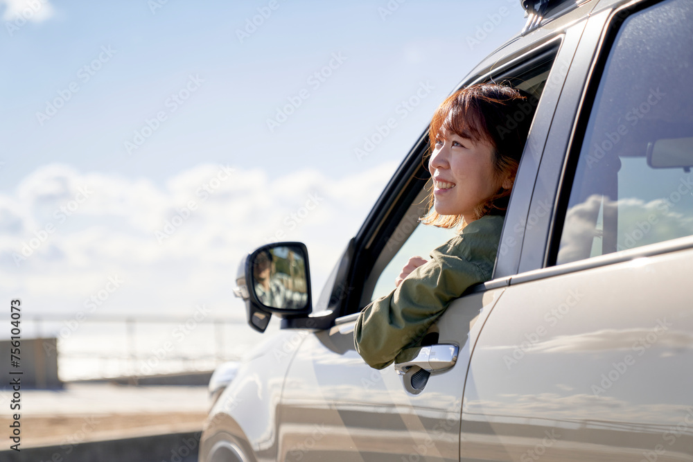 車の助手席で窓の外を見て笑う女性 車の助手席で窓の外を見て笑う女性