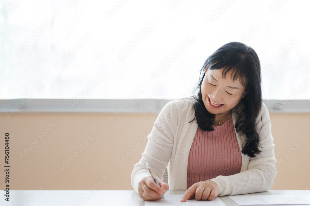 書類を記載する私服の中年女性