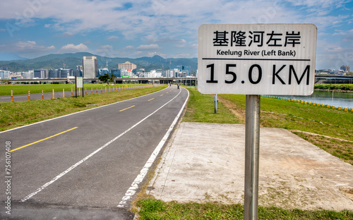 Paved path alongside the Keelung River in Taipei with mileage sign