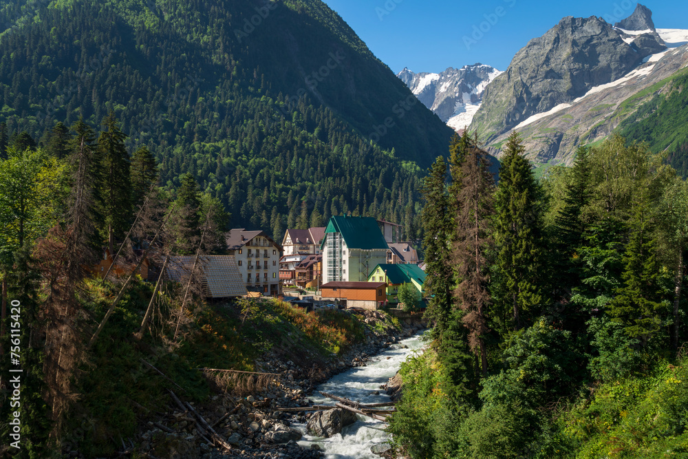 View of Dombai ski resort on the banks of the Amanauz River at the foot of the mountains of the North Caucasus on a summer day, Karachay-Cherkessia, Russia