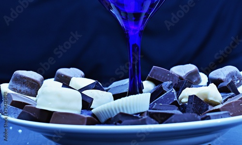Assorted chocolates arranged around a blue wine glass. (ID: 756121698)