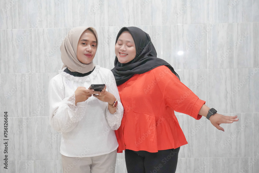 The happy expression of two women wearing hijabs in white and red clothes