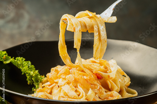 photograph of fettuccini carbonara noodles with tomato sauce garlic various seasonings in an old frying pan giving flavor to the food