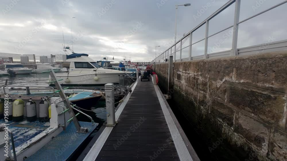 Walking along the Port of Tarifa, past yachts and fishing boats, on a cloudy afternoon Walking along the Port of Tarifa, past yachts and fishing boats, on a cloudy afternoon