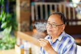 An elderly Thai man is smoking a cigarette. The concept of harming health.