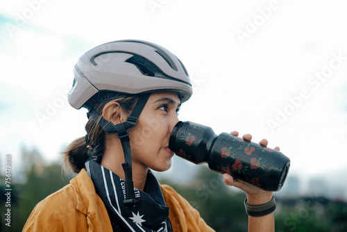 Fotografie A young woman cyclist is drinking from her water bottle.