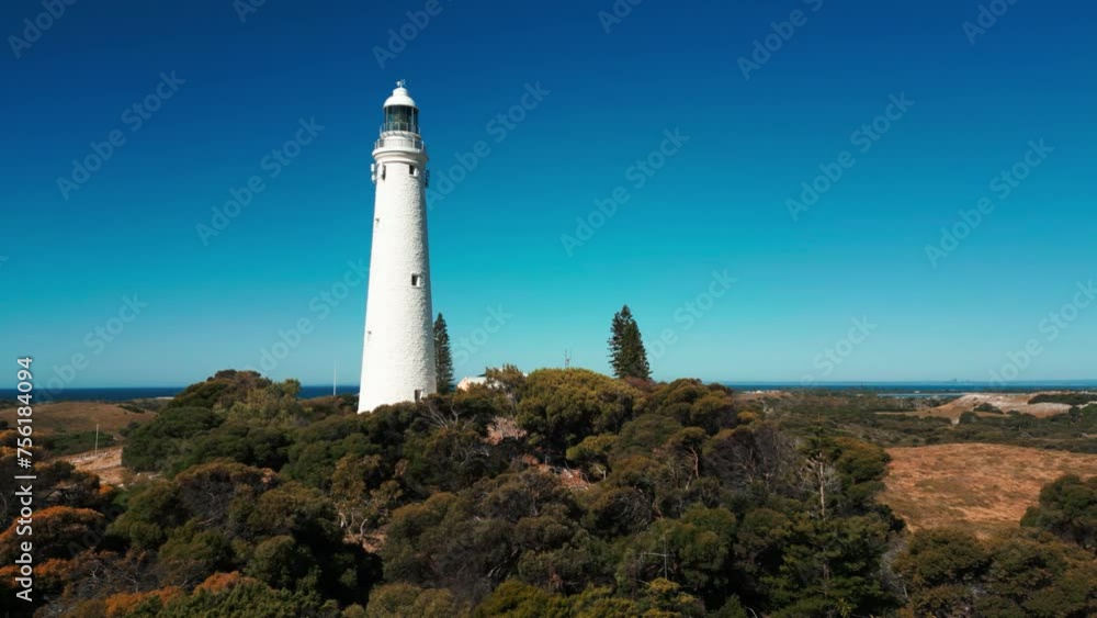 drone shot flying close by wadjemup lighthouse on Rottnest Island on a sunny day revealing the landscape in the background, Western Australia