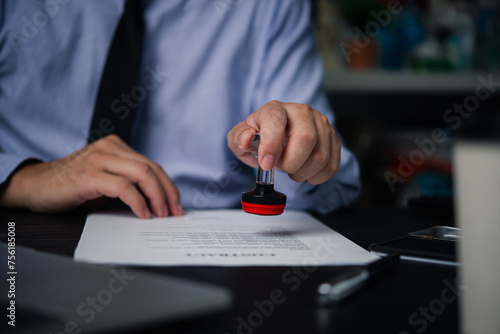 Man stamping approval of work finance banking or investment marketing documents on desk..