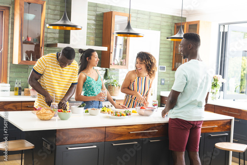 Diverse group of friends preparing food together in a modern kitchen