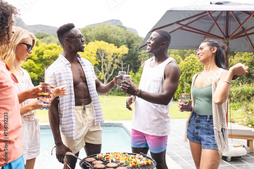 Diverse group of friends enjoys a barbecue by the pool