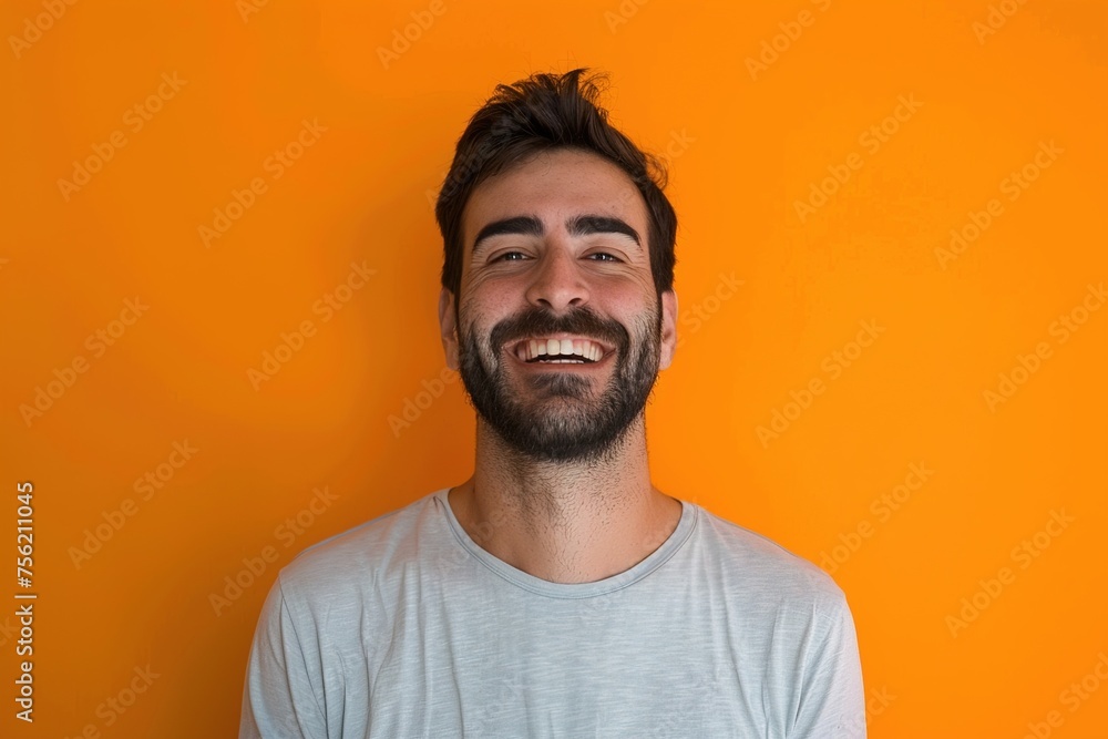 Fototapeta premium A man with a beard and a smile is standing in front of an orange wall