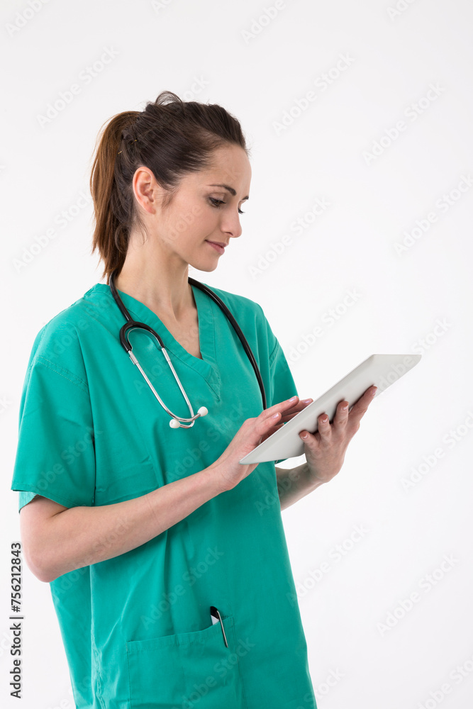 Healthcare worker wearing uniform and stethoscope reading Tablet device.