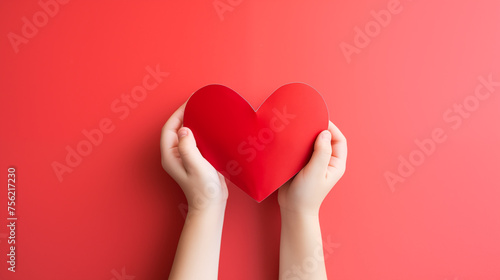 Hands holding blank paper greeting or invitation card over red background with heart shape. Christmas, Valentine day, New Year, winter holidays concept.