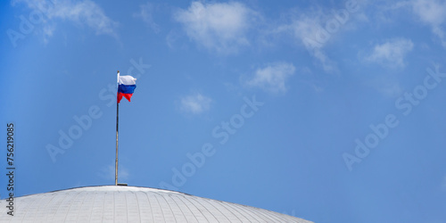 The flag of the Russian Federation on the dome of the building against a clear blue sky