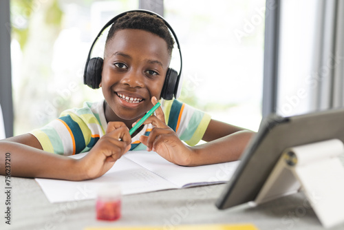 African American boy with headphones studies online at a tablet photo