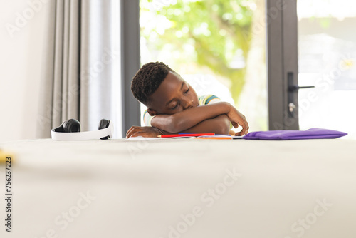 African American boy appears bored with his head resting on his arms photo