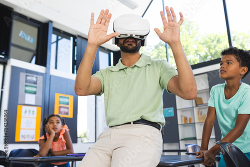 Young Asian male teacher explores virtual reality, wearing a VR headset in a classroom in school photo