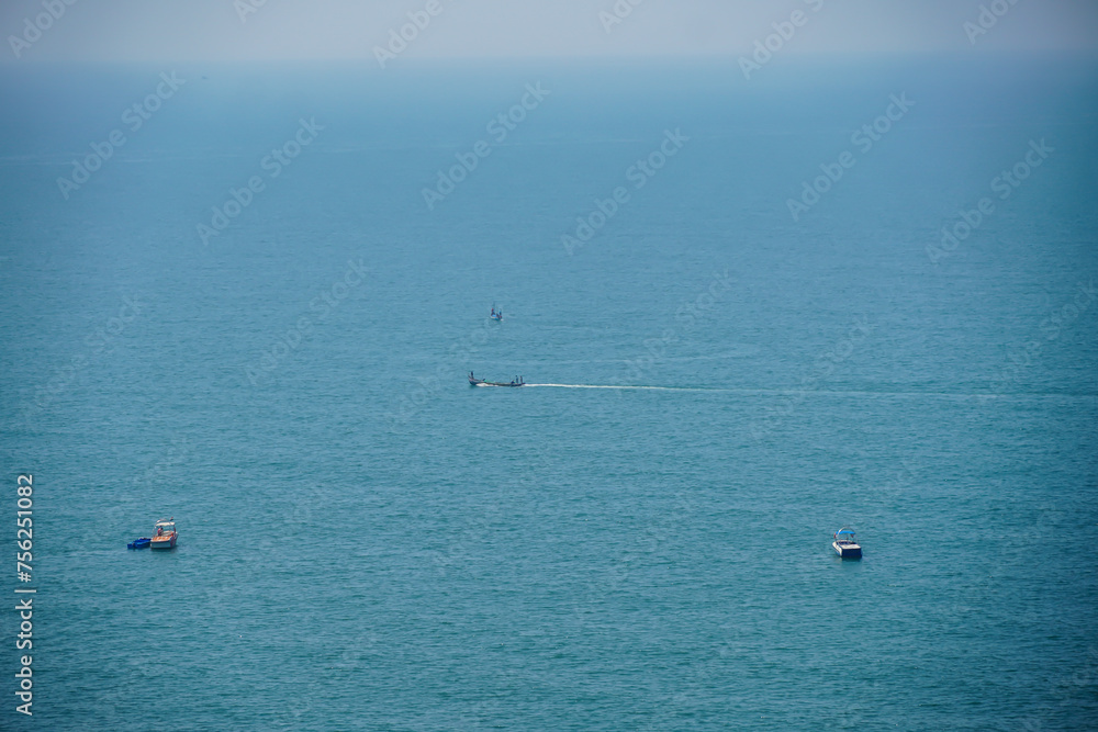 AERIAL: Fishing boat leaves a trail in the calm ocean water as it speeds towards endless horizon on a picturesque summer day. Four boats can be seen into the vast open ocean. White boats in blue water