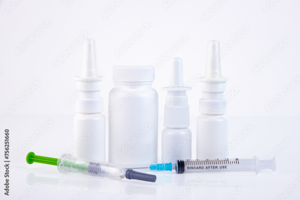 Nasal sprays, syringes, white medical jar for pills on a white background Concept of treatment of flu, virus, cold. Copy space. Nasal sprays, syringes, white medical jar for pills on a white background Concept of treatment of flu, virus, cold. Copy space.