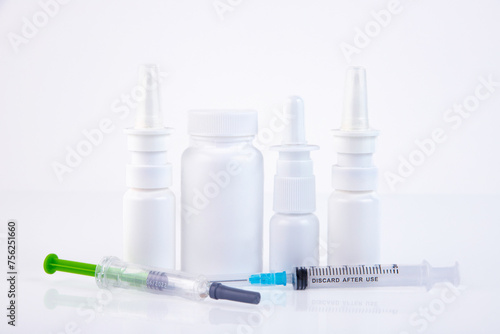 Nasal sprays, syringes, white medical jar for pills on a white background Concept of treatment of flu, virus, cold. Copy space.