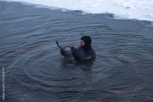A man in a diving suit. A professional rescue diver is in the hole and ready to help a drowning person.