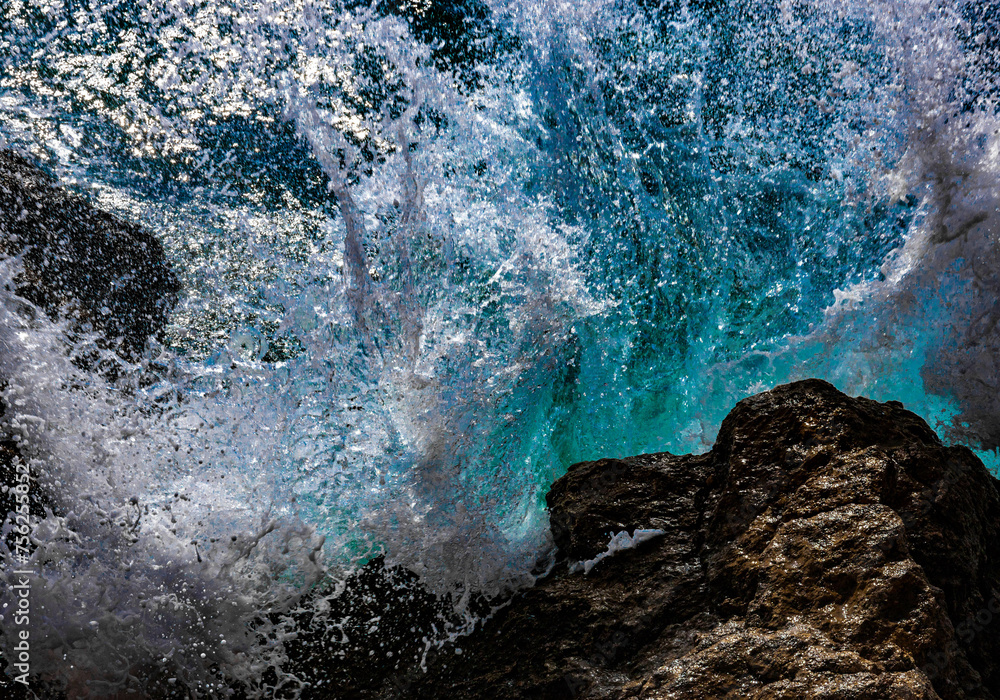 Turquoise waves of sea water break and spray drops on stones. Close-up. Red sea Turquoise waves of sea water break and spray drops on stones. Close-up. Red sea