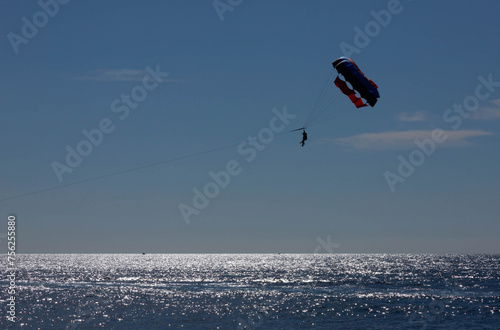 Tourists fly over the sea and the beach on a parachute