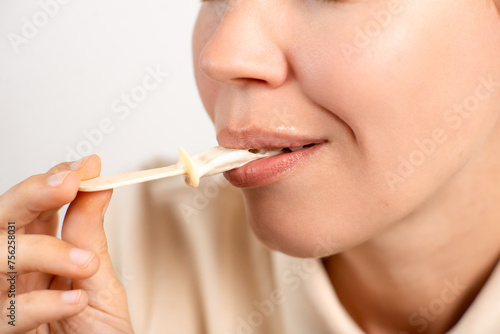 Close-up of an unrecognizable woman finishing her ice cream on a stick on a white background. Sweet tooth, dessert