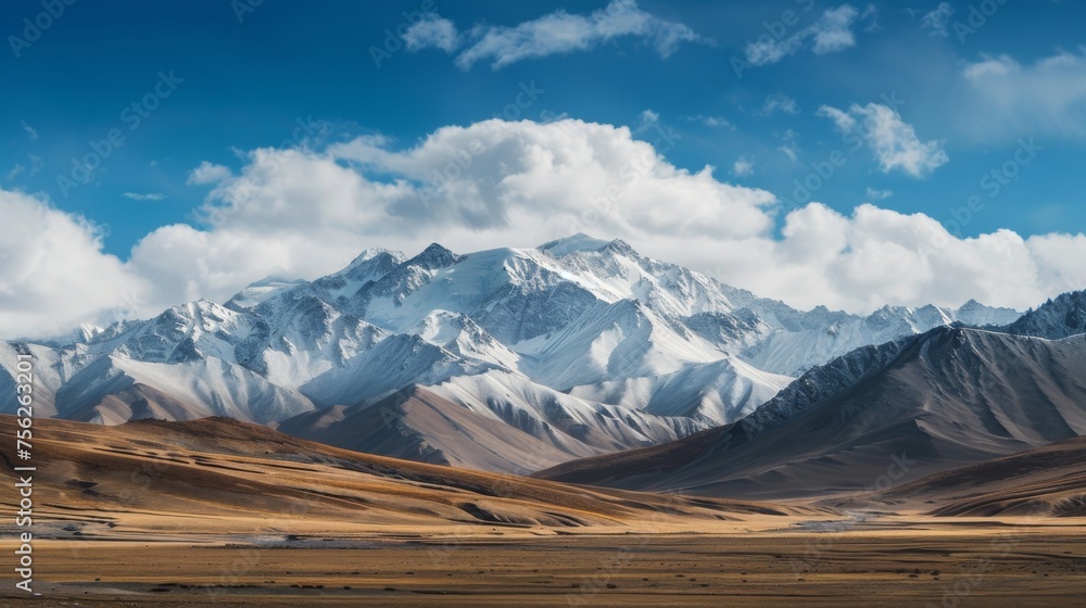 Majestic snow-capped mountains under a blue sky with clouds, over a vast, open landscape