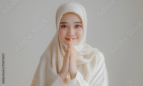 Indonesian hijab-wearing woman raises her hand while smiling (ID: 756274637)
