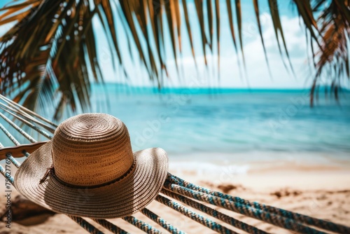 a hammock with a straw hat on it placed on the beach with a view of the ocean - travel concept