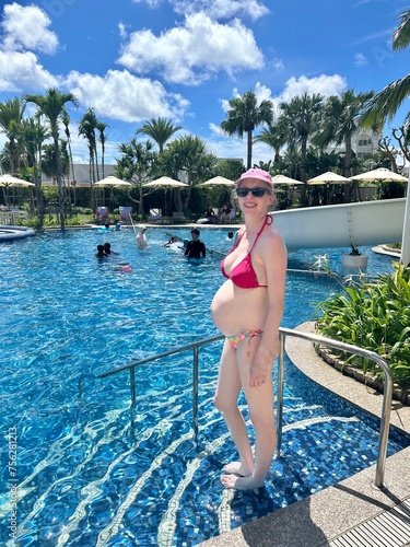 Jeune femme enceinte portant un bikini devant une piscine